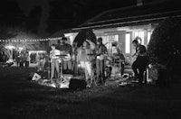 a black and white photo of a group of people in front of a house