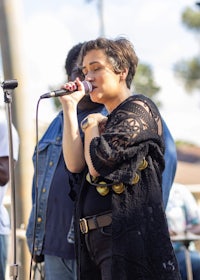 a woman singing into a microphone in front of a group of people