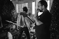 a black and white photo of a group of people playing music in a house