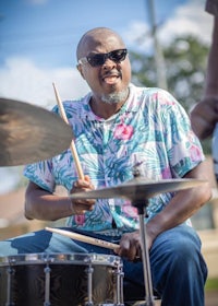 a man in sunglasses playing drums on a street